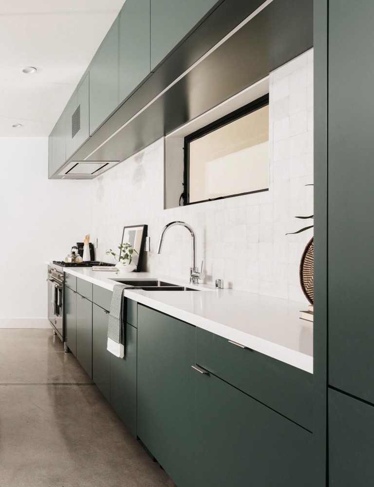 The kitchen is designed in dark green and white, with a chic tile backsplash and a matching white countertop