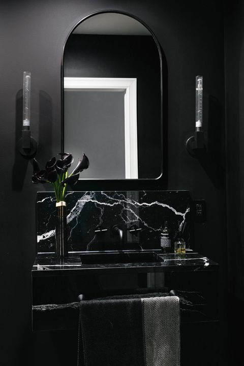 a chic moody bathroom in black and graphite grey with a marble wall-mounted sink