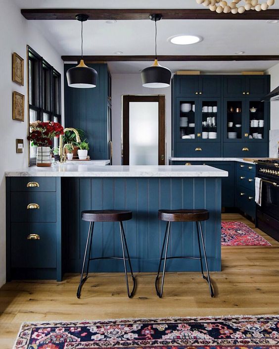 a chic navy kitchen with white stone countertops, dark wooden beams and chairs for a contrast