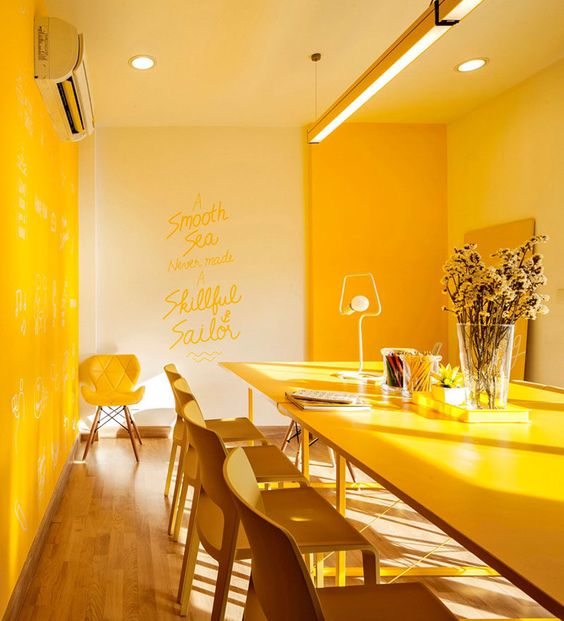 An ultra modern dining space done in yellow   with bright furniture, built in lights and yellow chairs