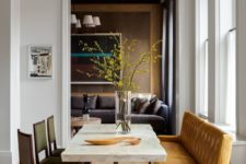 08 a chic dining room with a stone slab table, leather chairs and a large amber-colored leather bench