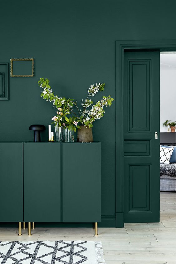 a monochromatic emerald green interior spruced up with gold touches and frames on the wall