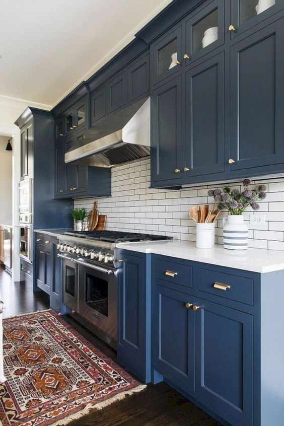 a navy kitchen with gold touches, a subway tile backsplash and a boho rug to add color to the space