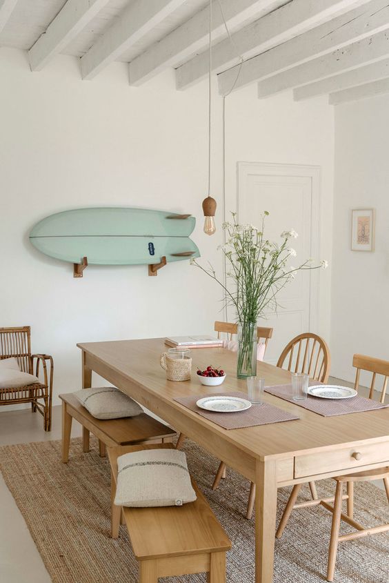 a coastal dining room with a simple wooden table and some mini benches that match - the furniture perfectly matches the style