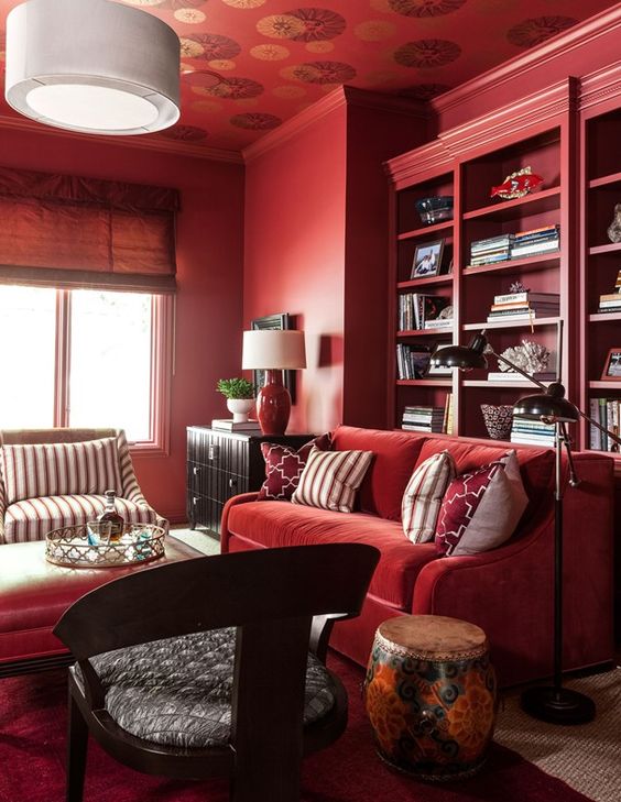 a monochromatic bold red living room with built-in shelves, comfy furniture and some dark touches for drama
