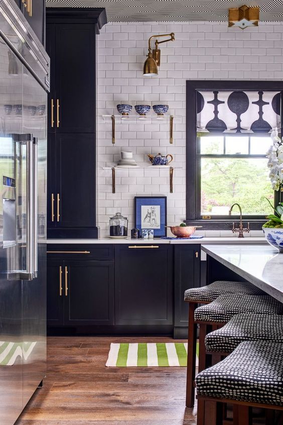 a navy kitchen with gold touches, a white subway tile backsplash and patterns feels retro and very chic