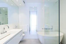 10 The bathroom is done in white, with lots of lights, a sleek floating vanity and a free-standing tub