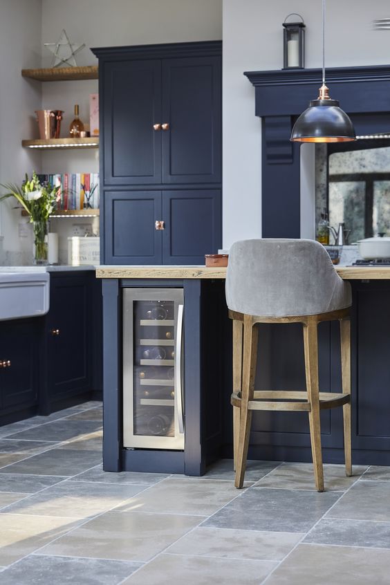 A retro navy kitchen with white and light colored wood touches and touches of copper that make it feel cozy