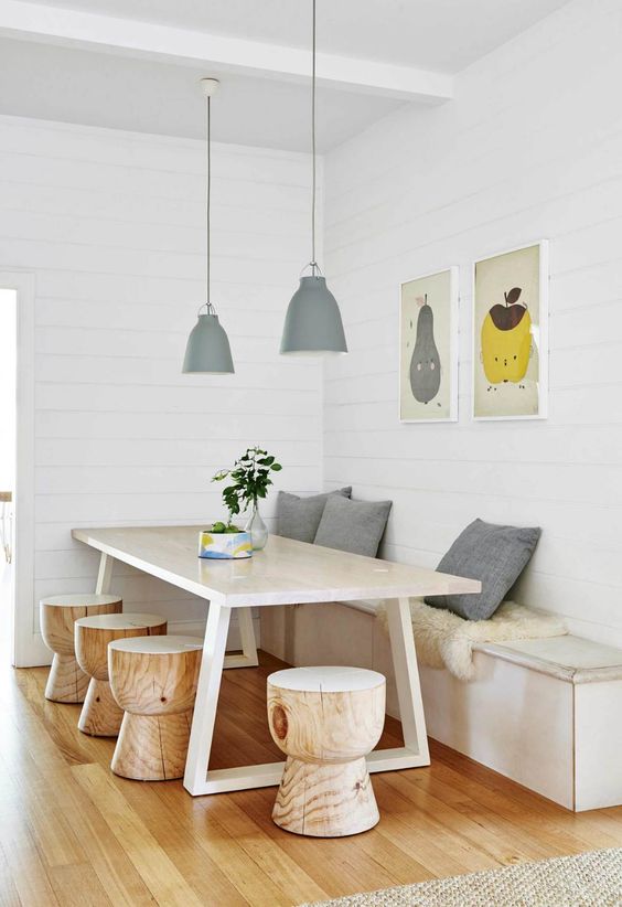 a chic dining space with a storage bench, a stylish wooden table and little round stools