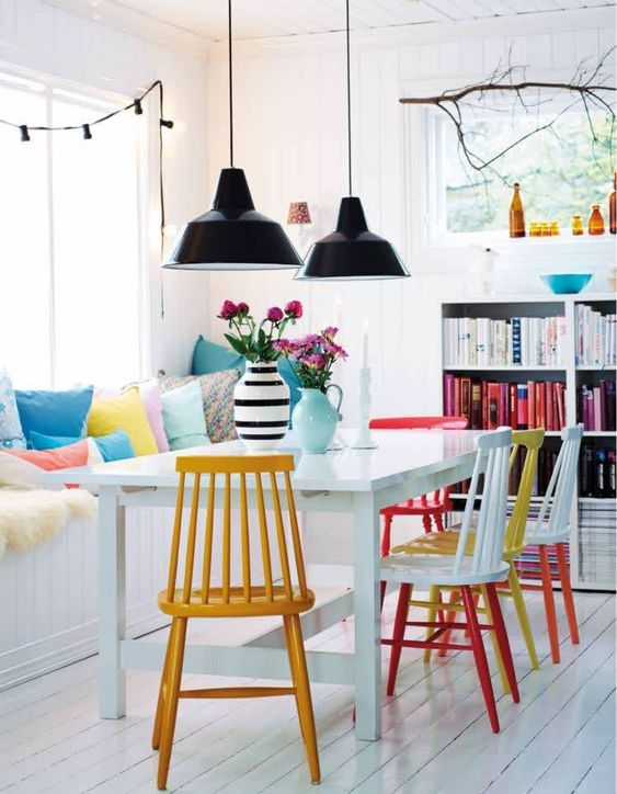 a neutral dining space is spruced up with colorful printed pillows and bright chairs that make a statement