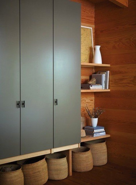 an IKEA Pax wardrobe in olive green, mounted on the wall and with open shelving