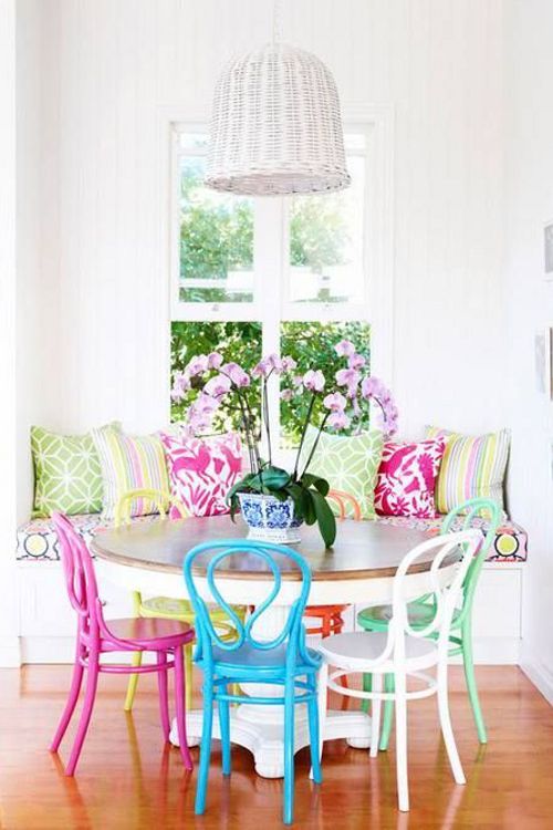 a bright dining space with super bright pillows and colorful chairs looks fun, cheerful and colorful