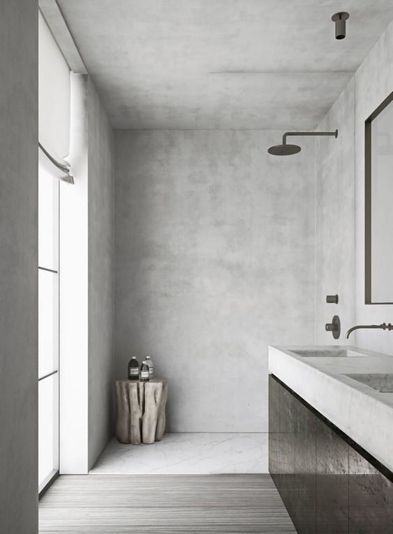 a light-colored bathroom done wiht concrete and dark stained furniture and a window