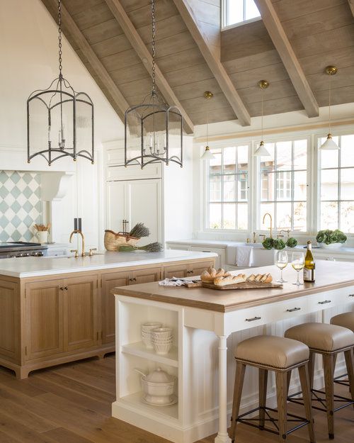 a neutral rustic kitchen with two kitchen islands that match, one for cooking and another for meals
