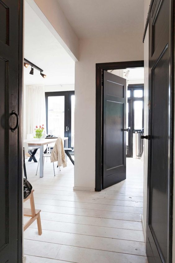a fully neutral and light-filled space gets some drama from black doors here and there