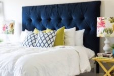 15 a navy tufted headboard is the main centerpiece of the bedroom, it brings color and makes a statement