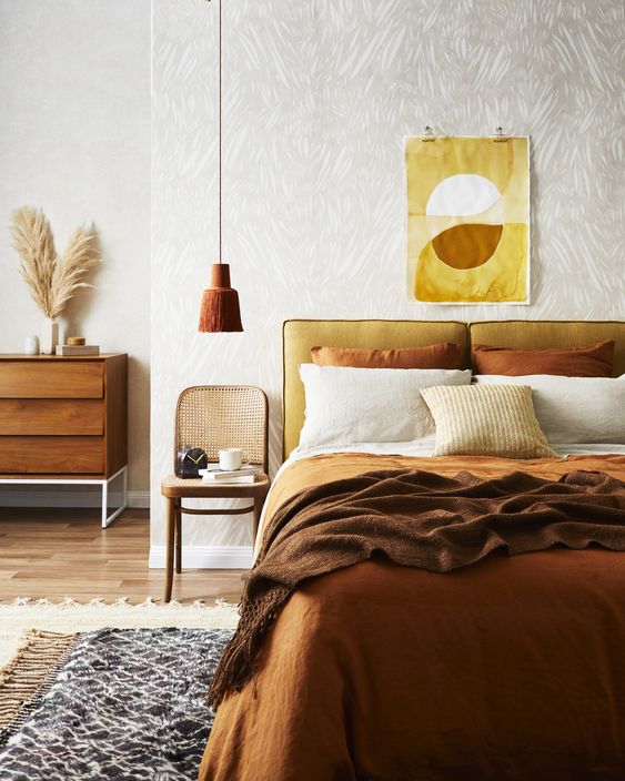 A fall colored earthy bedroom in ocher, yellow, mustard and rust shades and with wood and rattan