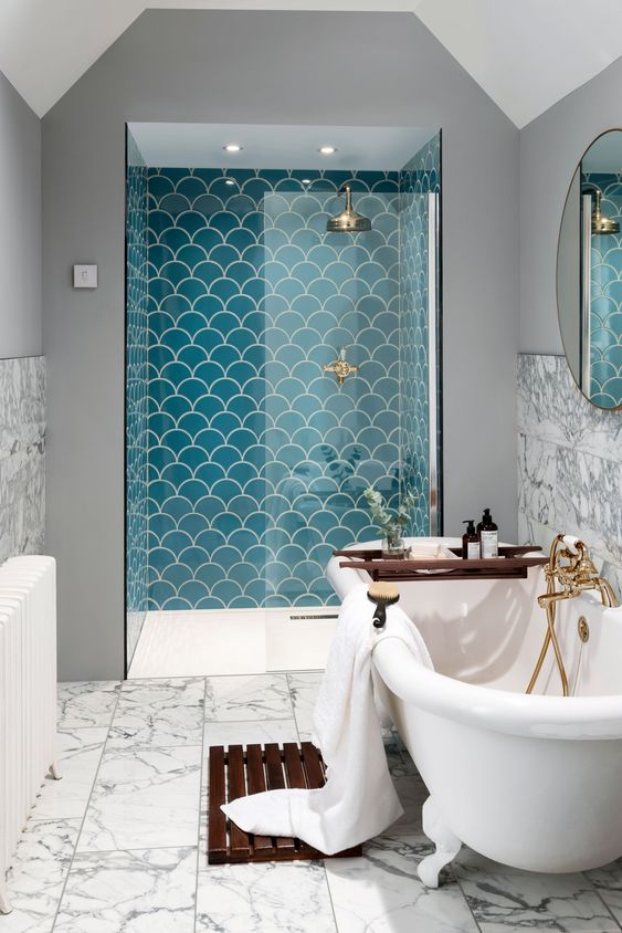 a shower space done with turquoise scallop shaped tiles that make it stand out a lot