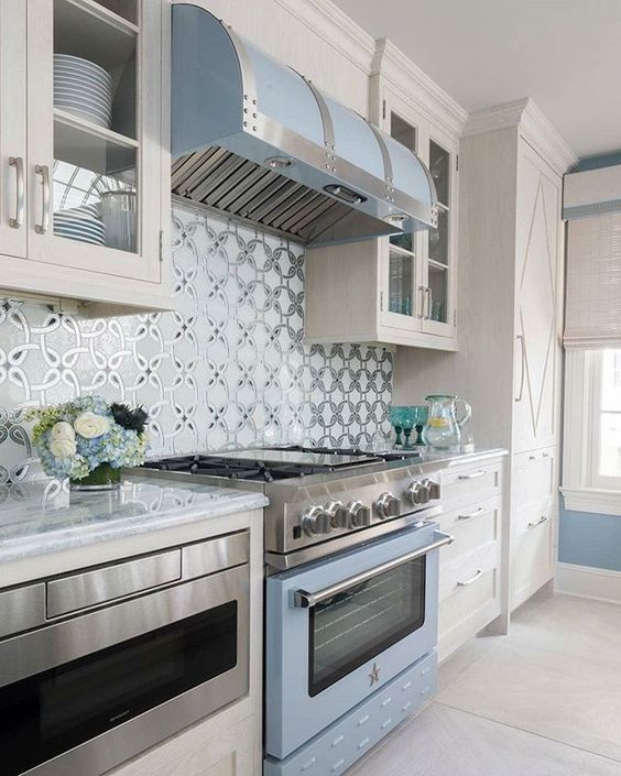 a light blue cooker and hood match the color of the walls and delicately infuse the neutral space with color
