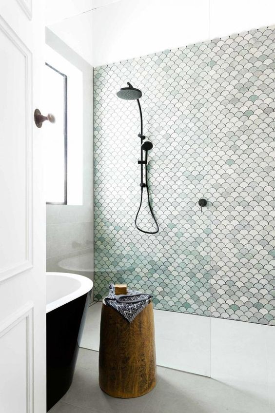 a neutral bathroom with a shower space done with aqua-colored scallop tiles that make it stand out