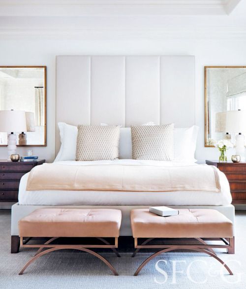 a statement white upholstered headboard and little pink stools to create a soft feel in the space
