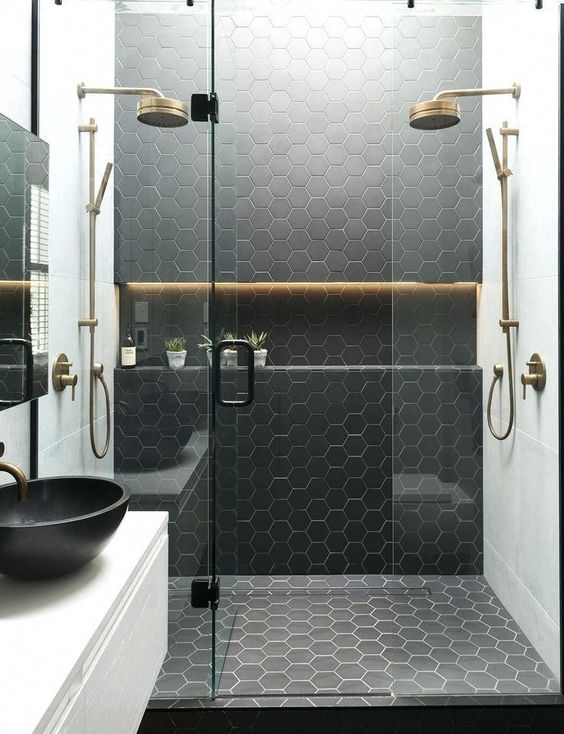 a black and white bathroom with hexagon tiles in the shower space and brass touches for more elegance