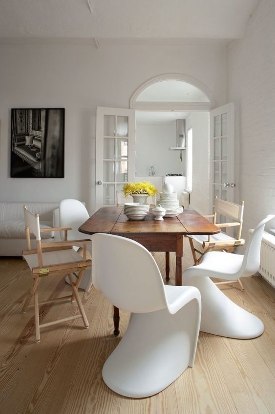 a chic dining room with a wooden table and totally mismatching chairs in the same color scheme