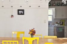 20 a dining room with a long wooden table and a number of mismatching chairs done in the same shade of yellow