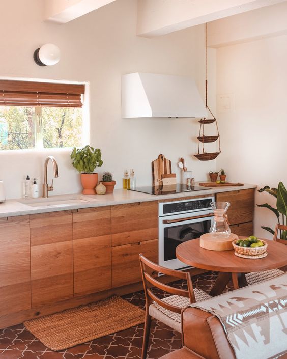 a warming and welcoming kitchen with wooden furniture, wooden shutters and natural greenery in pots