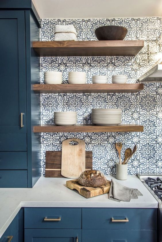 Light colored wooden open shelves stand out in  the blue mosai tiles and add a warm touch to the space