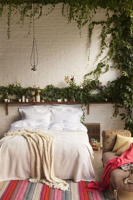 a boho bedroom with vines covering the wall over the bed that bring a fresh feel here