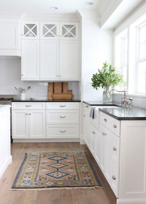 a classic white kitchen with black countertops that create interest due to the contrast they bring