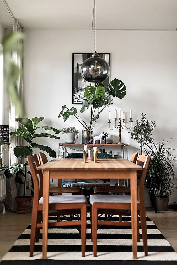 greenery in vases and pots and a green chair make the monochromatic dining room brighter and fresher