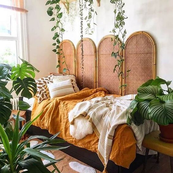 potted statement plants and some vines hanging over the bed make the bedroom feel tropical