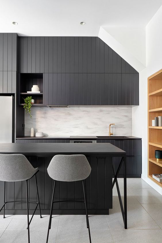 a dark kitchen with dark countertops is a stylish idea and a neutral backsplash adds contrast to the space