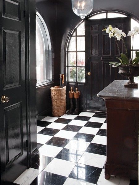 a refined and chic black and white entryway with a checked floor and black doors looks really wow