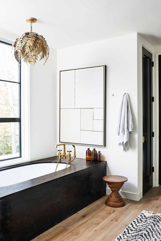 a refined bathroom with a black clad bathtub that is the centerpiece of this space