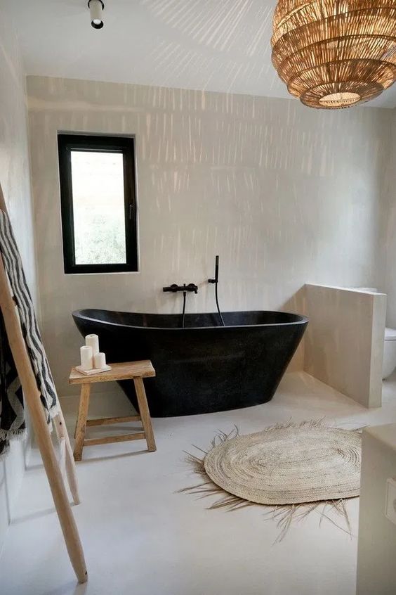  a minimalist meets boho bathroom with a black stone bathtub and some touches of jute and wood