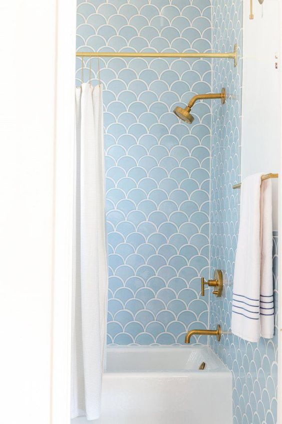 light blue scallop tiles and brass fixtures create a cool and chic combo for a bathroom