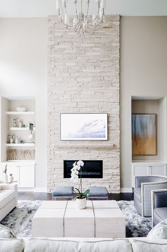 a clean neutral living room with a white faux stone fireplace and some pastel blue touches here and there