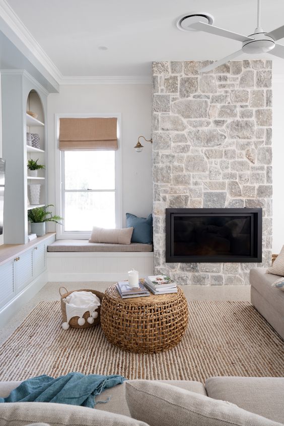 A contemporary living room with a built in fireplace, grey seating furniture, a jute rug, niche shelves and greenery