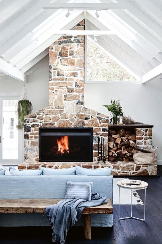 a contemporary living room with blue furniture, a stone hearth with a built-in modern fireplace and skylights