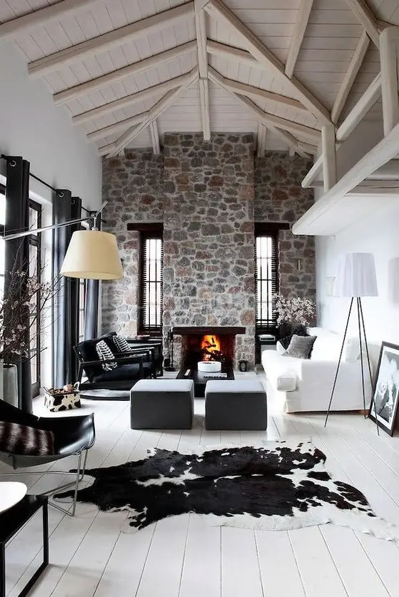 a contemporary living room with white walls, a whitewashed wooden ceiling, a stone clad fireplace and cool furniture