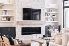 a contrasting living room with a stone fireplace, shelves and built-in cabinets, a white sofa, black chairs, a black side table
