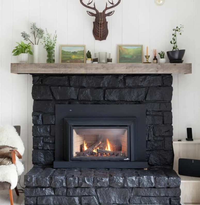 a large black stone clad fireplace with a wooden mantel is a great cabin or woodland touch to the space