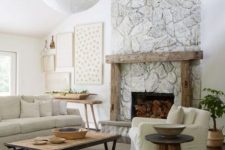 a neutral living room with a whitewashed stone fireplace, a wooden mantel and furniture, a gallery wall and a potted plant