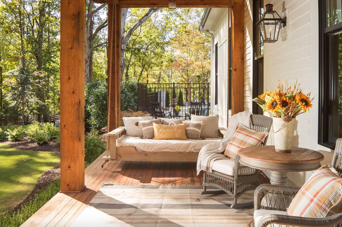 The front porch is very cozy, with wooden and wicker furniture and cozy textiles