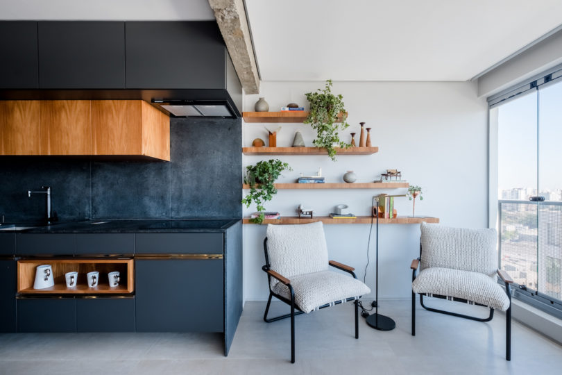 The kitchen is done in black, with matte surfaces, rich colored wooden touches and gold shiny ones