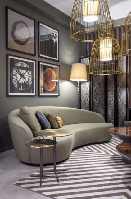 a catchy living room with a retro feel and a curved taupe sofa, a bold gallery wall and gold wire pendant lamps