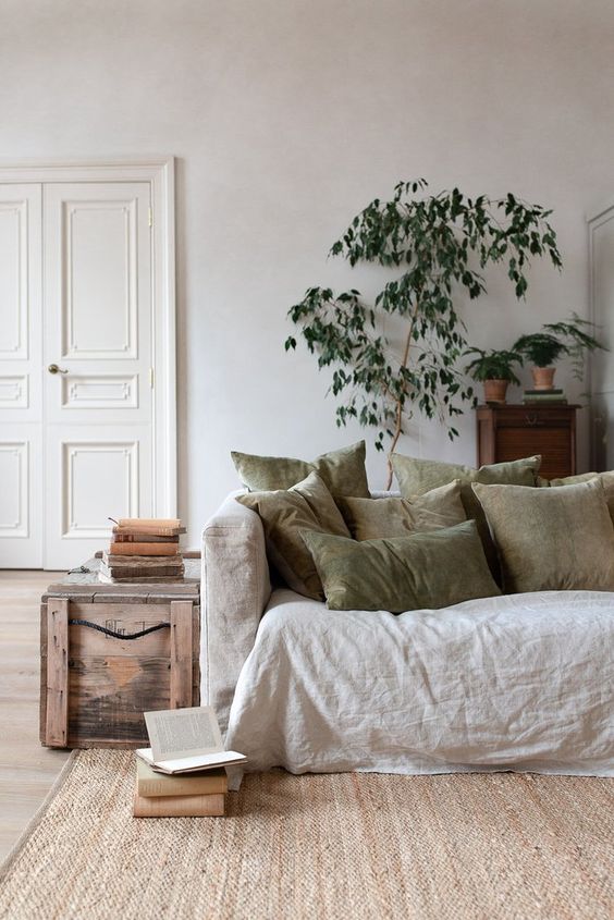 a neutral living room in various soft shades with plenty of texture and potted greenery and a tree